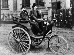 Evolution: Die verbesserte Ausführung des Benz Patent-Motorwagens, vorgestellt 1888, hat bereits Kotflügel über den Hinterrädern. Rechts im Bild: Carl Benz.