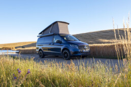Der neue Mercedes-Benz Marco Polo gefertigt im Mercedes-Benz Werk in Ludwigsfelde – Sodalithblau metallic, MBUX Multimediasystem, Widescreen Cockpit, Polster Leder Lugano schwarz, Camper-Umfänge u.a. Markise, Kleiderschrank, Küchenzeile mit Klapptisch, Drehbare Fahrer- und Beifahrersitze, Sitzliegebank, Aufstelldach mit Dachbett, MBAC Camper-Bedieneinheit (Ausgewählte Features erst im Jahresverlauf 2026 erhältlich; Landesspezifische Vorschriften zum Wildcampen sind zu beachten, Aufnahmen auf Privatgrundstücken entstanden)